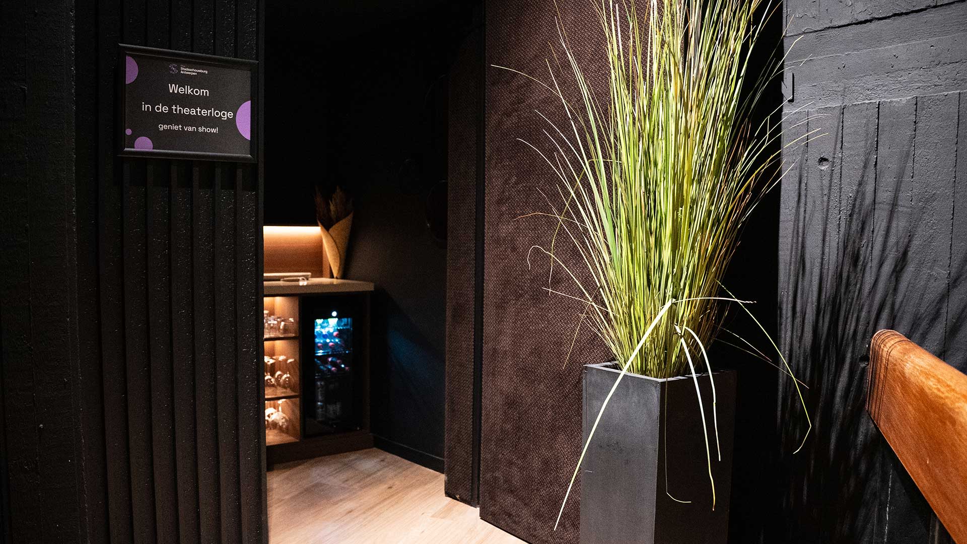 Ingang van een theaterloge met welkomstbordje en minibar