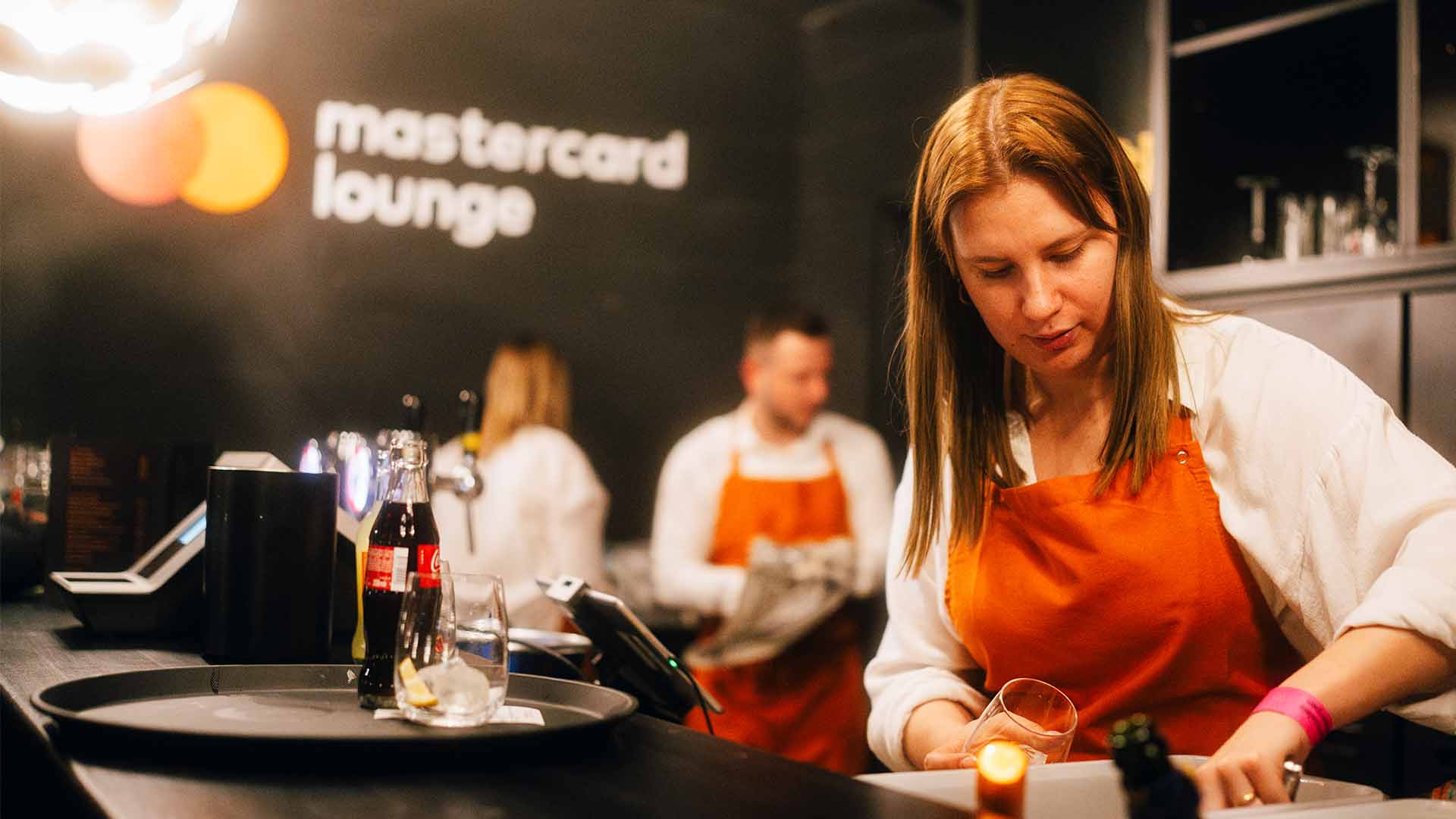 A bartender is filling a glass with ice cubes.