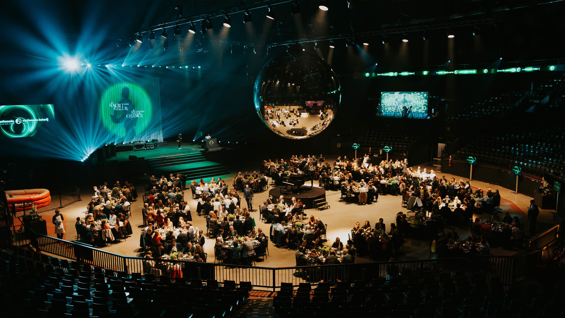 The central square of Forest National with large round tables in the middle and a large disco ball above them.
