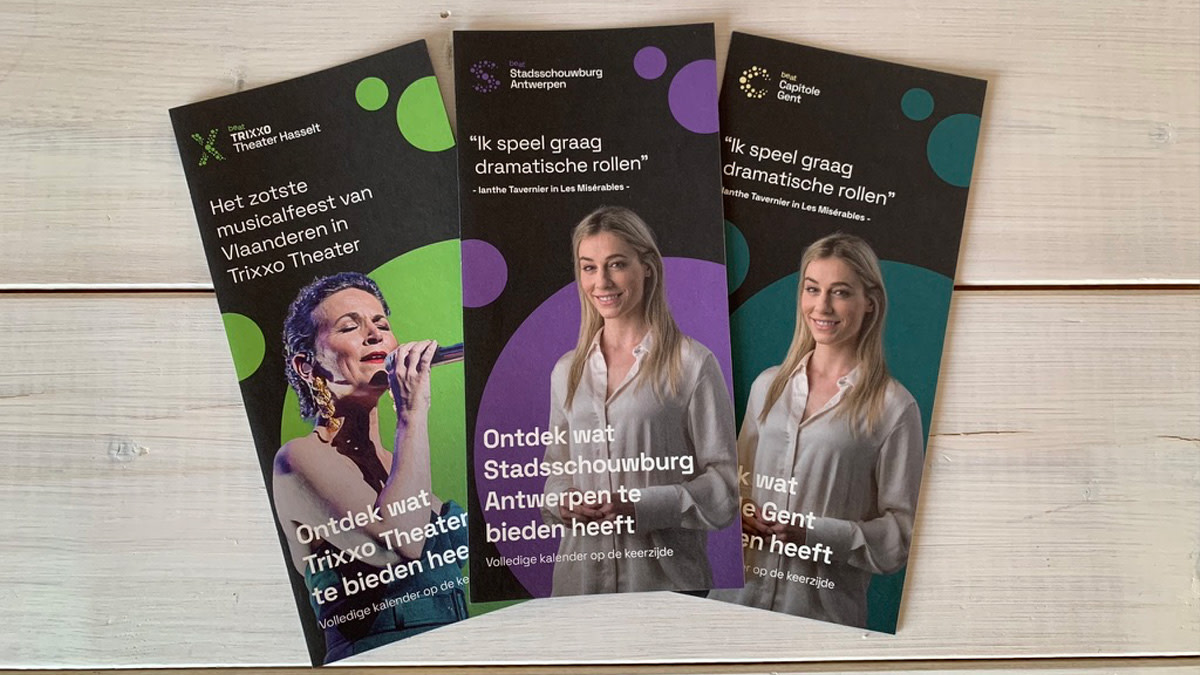 Beeld met drie theaterfolders op een houtachtige achtergrond.