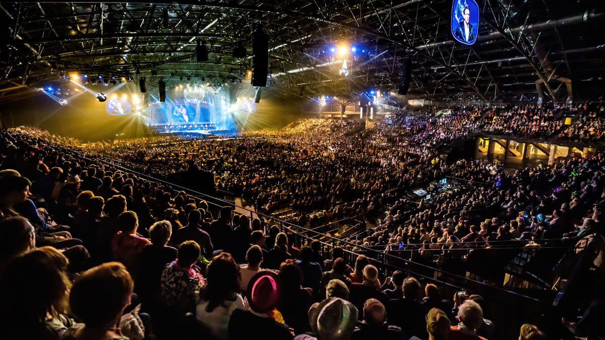 Een volle Trixxo Arena in Hasselt tijdens Het Schlagerfestival, met duizenden fans die genieten van een kleurrijk podium en liveoptredens.