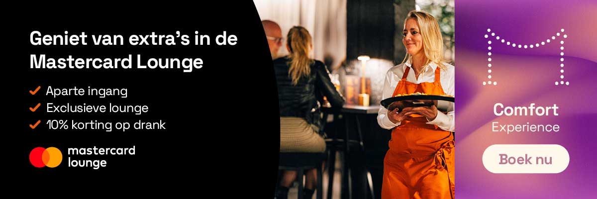 Interieur van de Mastercard Lounge met een medewerker die drankjes serveert aan staande bezoekers in een loungeomgeving.