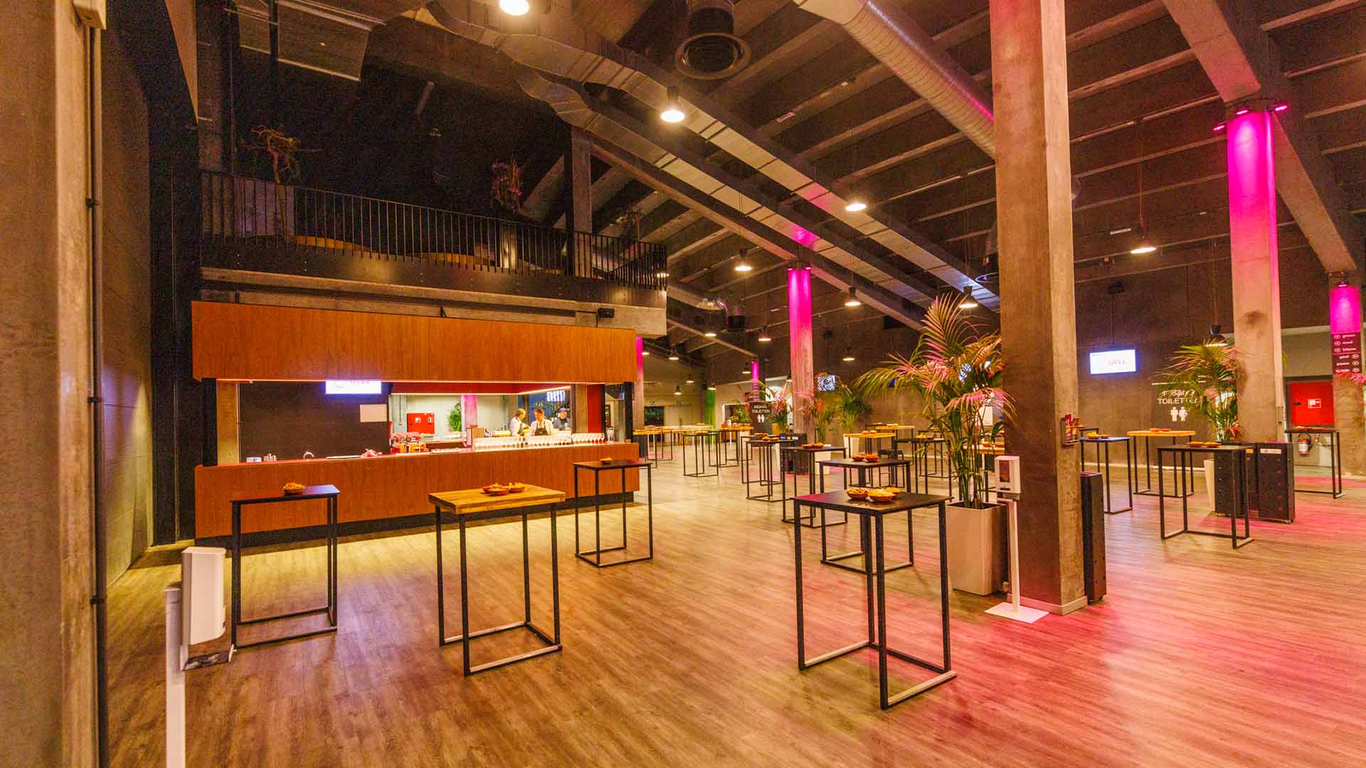Een lege foyer in Trixxo Theater Hasselt. Overal staan hoge tafeltjes en in de achtergrond is de bar te zien.