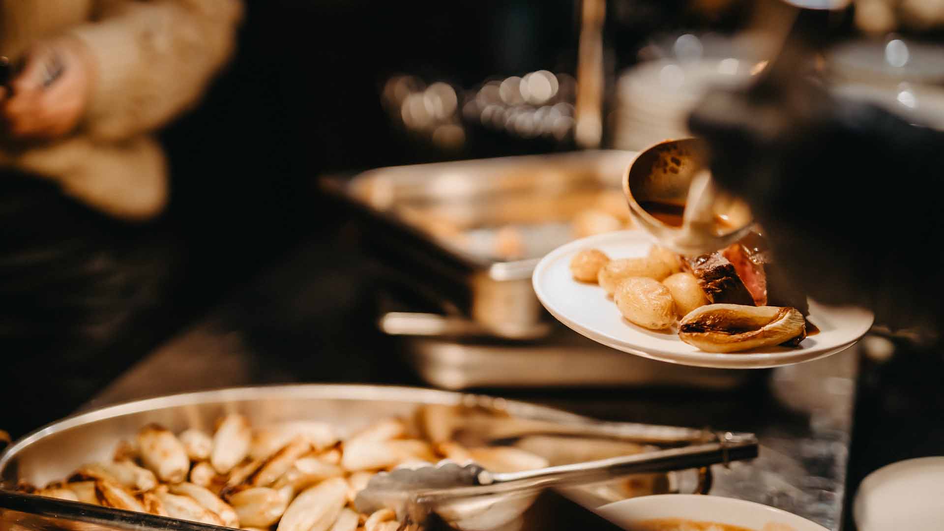 Een bord met warm eten, zoals aardappelen en vlees, waar saus over wordt gegoten.