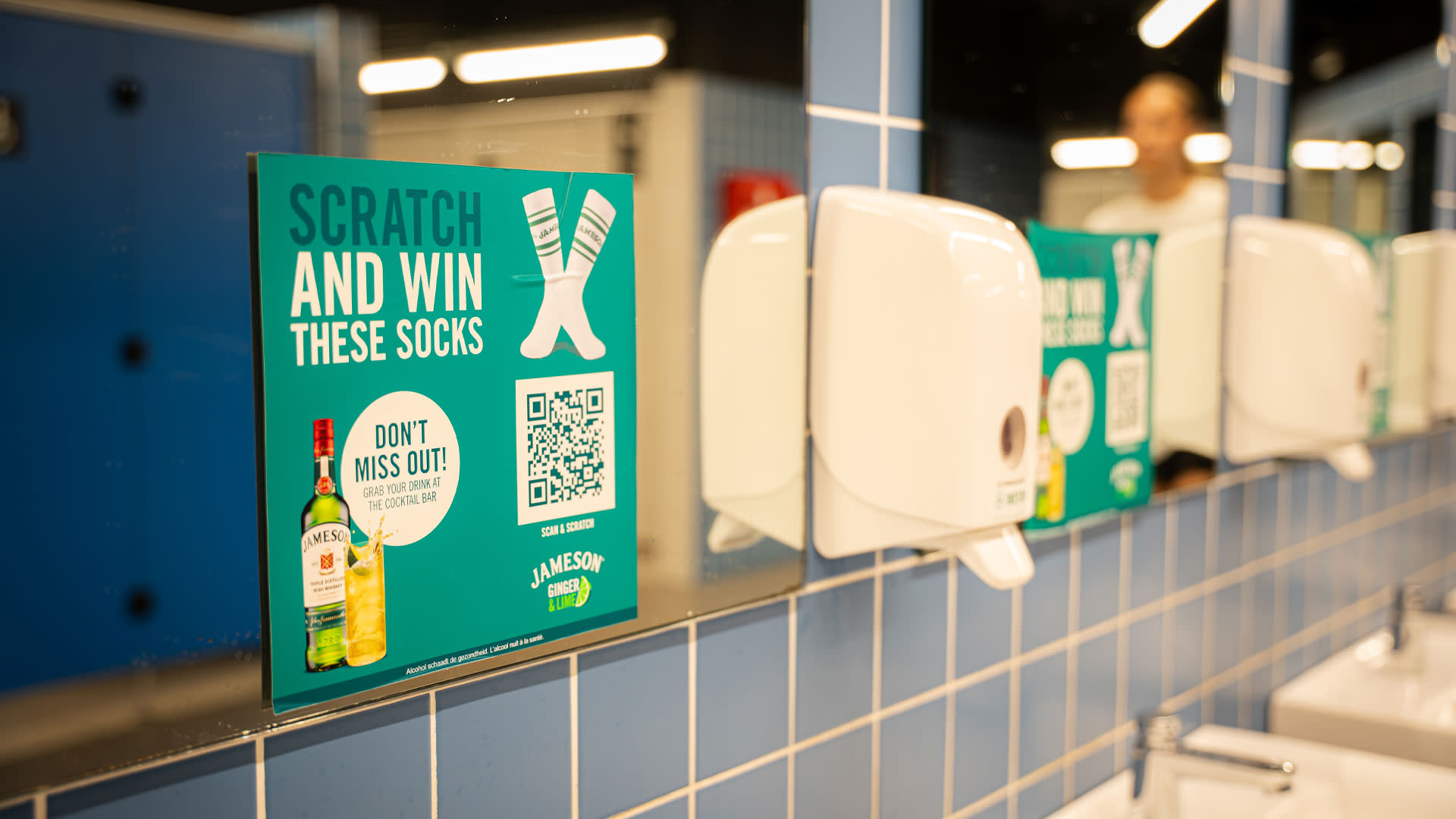 Jameson-promotiemateriaal met QR-code in de AFAS Dome dat concertbezoekers uitnodigt om deel te nemen aan een online Scratch & Win-actie en exclusieve merchandise te winnen.