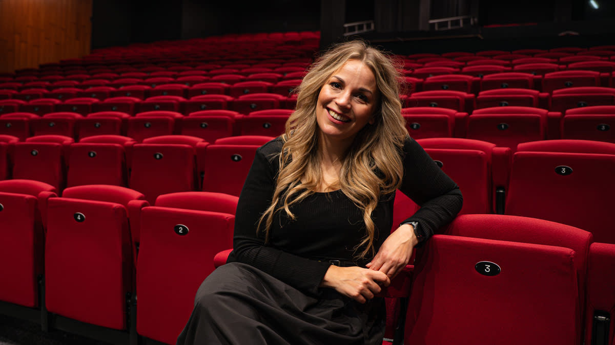 Laura Ramaekers zit volledig in het zwart gekleed in de theaterstoeltjes van Stadsschouwburg Antwerpen.