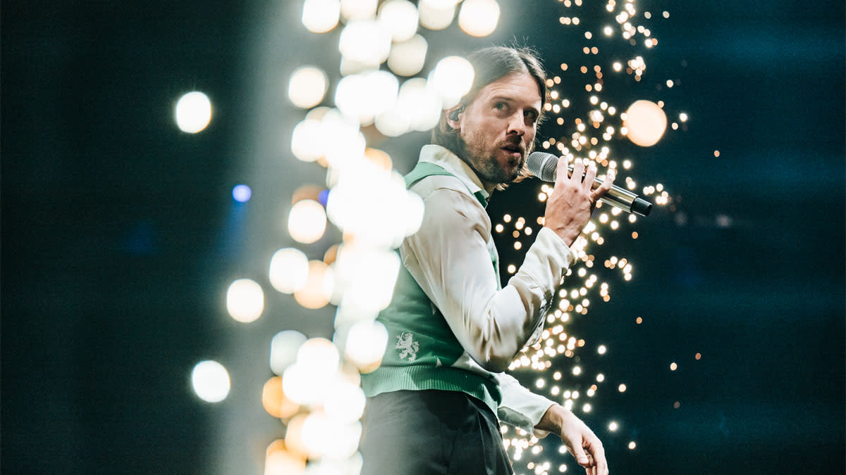 Mathieu Terryn met microfoon gehuld in glitters op het podium van 'Junior Eurosong' in de Lotto Arena.