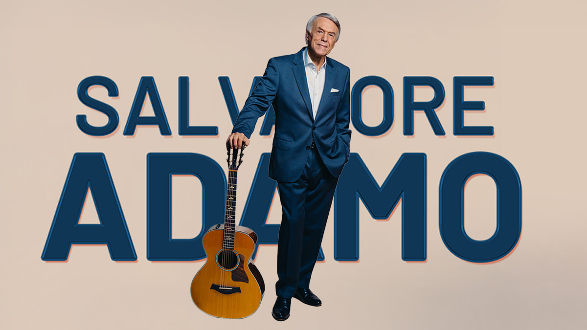 Salvatore Adamo in strak pak en een klassieke gitaar in de hand straalt van zelfvertrouwen.