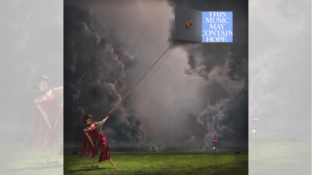 Op de afbeelding zie je zangeres Raye op een grasveld tegen een dreigende onweerslucht.