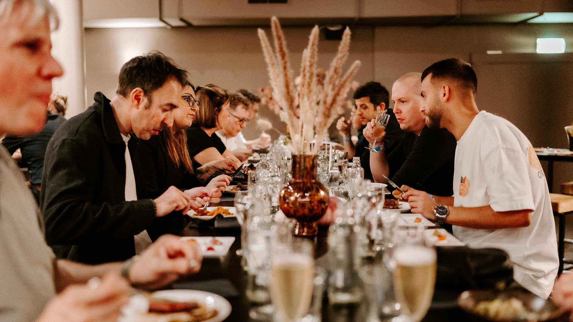 Bezoekers genieten van een diner tijdens een Premium Experience in Vorst Nationaal, met tafel gedekt met glazen en gerechten.