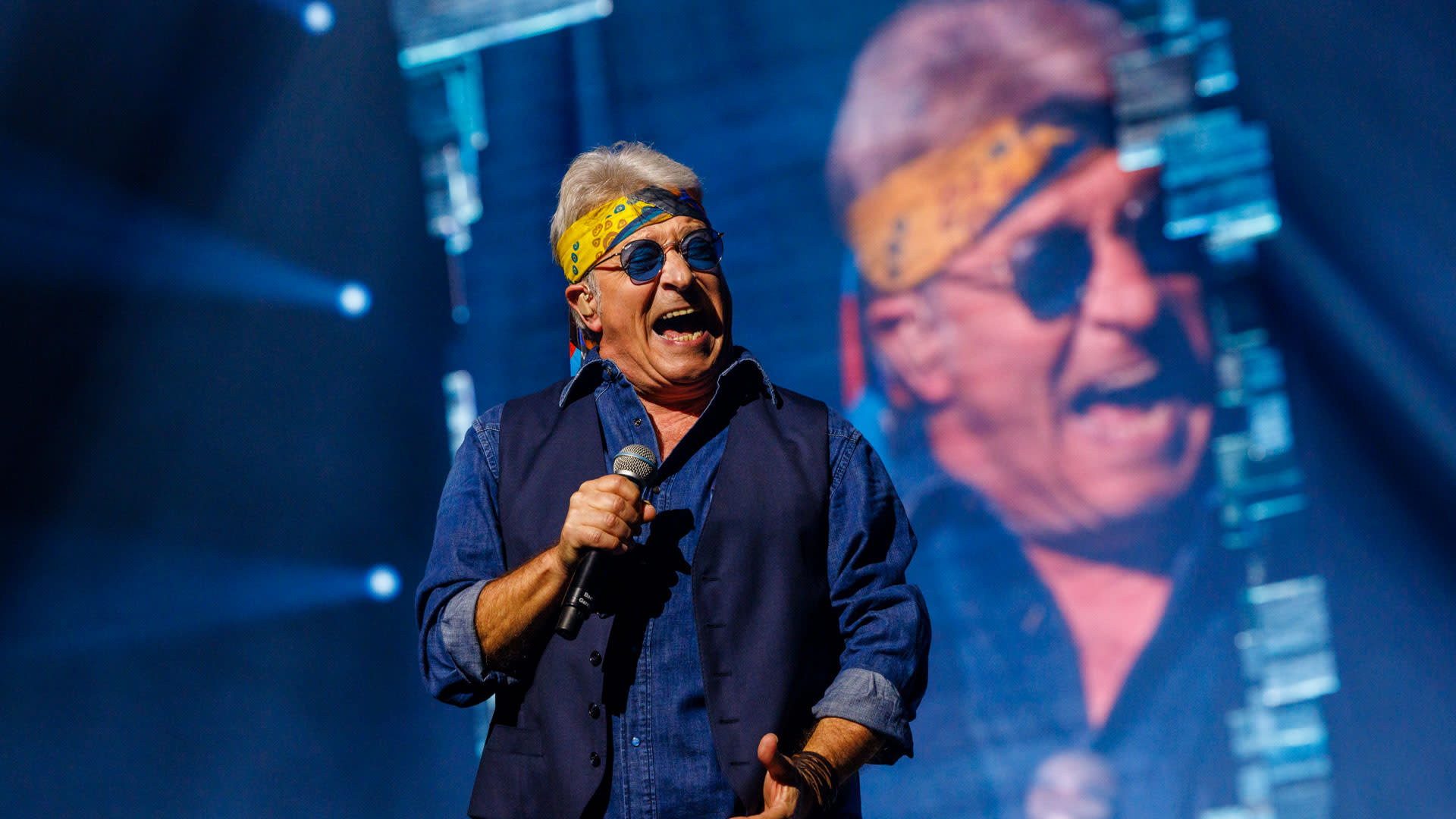 Garry Hagger zingt met een microfoon op het podium tijdens Het Schlagerfestival 2026, met zijn portret op het grote scherm achter hem.