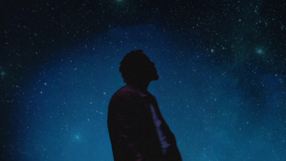 De foto toont een silhouet van Myles Smith tegenover een zwarte sterrenhemel.