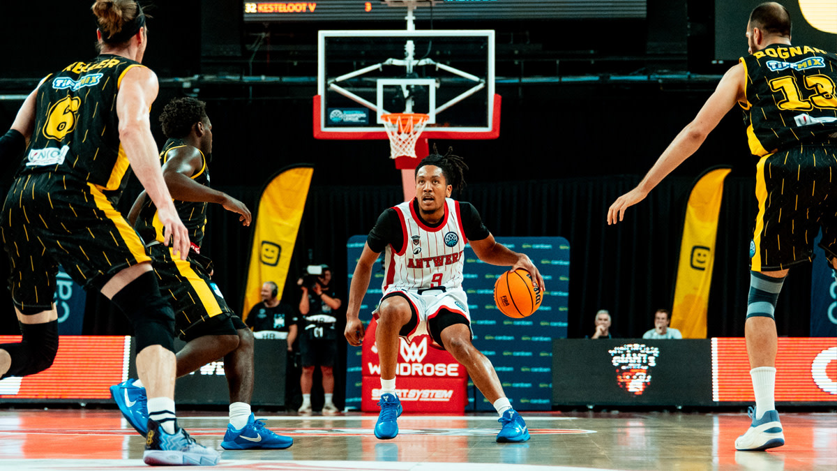 Een speler van Windrose Giants Antwerp staat op het basketbalveld oog in oog met drie spelers van de tegenpartij.