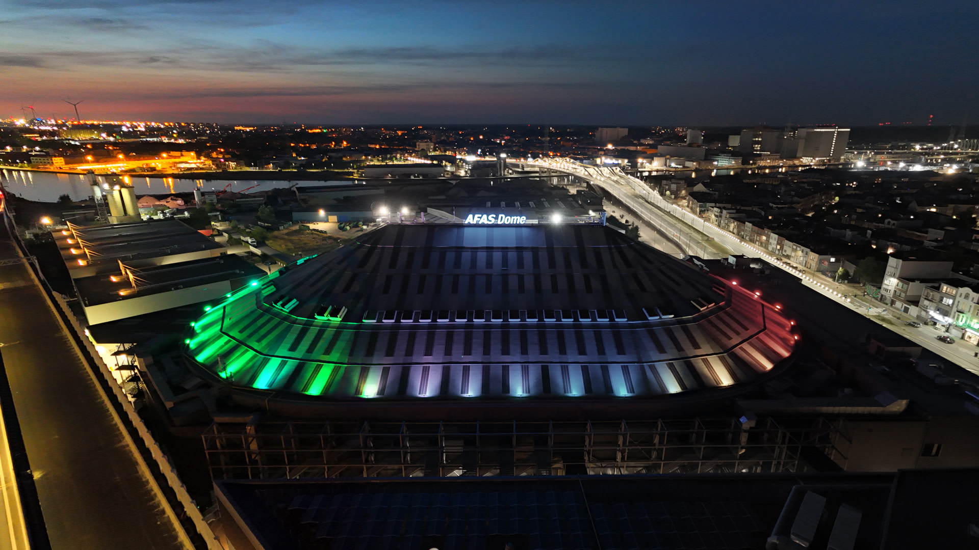 Luchtfoto van de AFAS Dome in Antwerpen, met het dak verlicht in regenboogkleuren voor Antwerp Pride 2026.