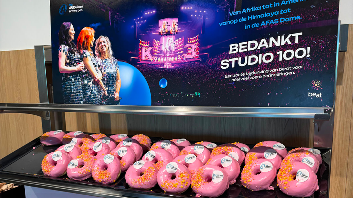 Een ruim aantal roze donuts op een groot dienblad.