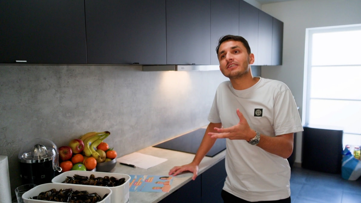 Comedian Mohsin Abbas in jeans en t-shirt in zijn keuken naar aanleiding van het televisieprogramma Komen Eten.