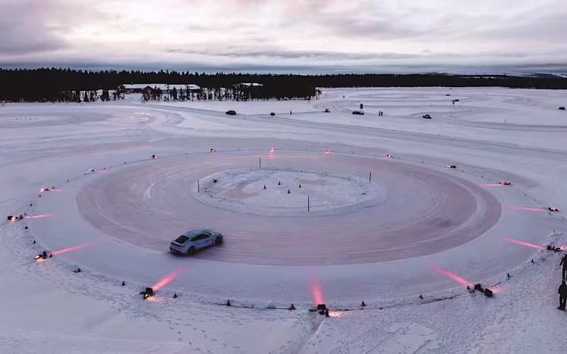 Porsche Taycan in frozenbluemetallic drifting in circles at sunset with red lighting.