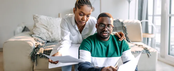 A financial advisor reviewing documents with a client in a living room.