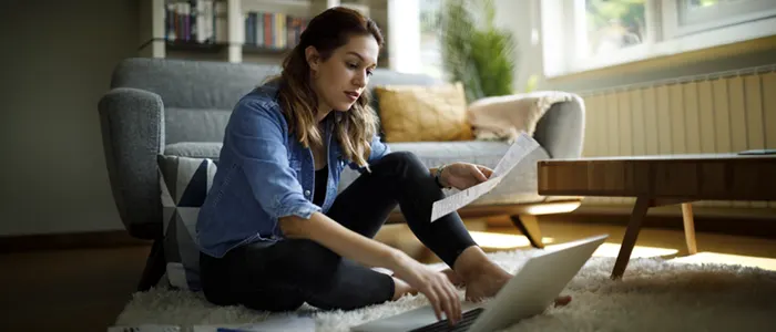 Woman reviewing financial documents on a laptop at home.
