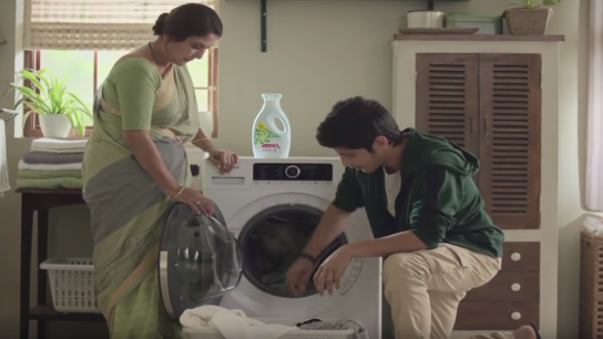 Mujer y hombre cargando ropa en la lavadora
