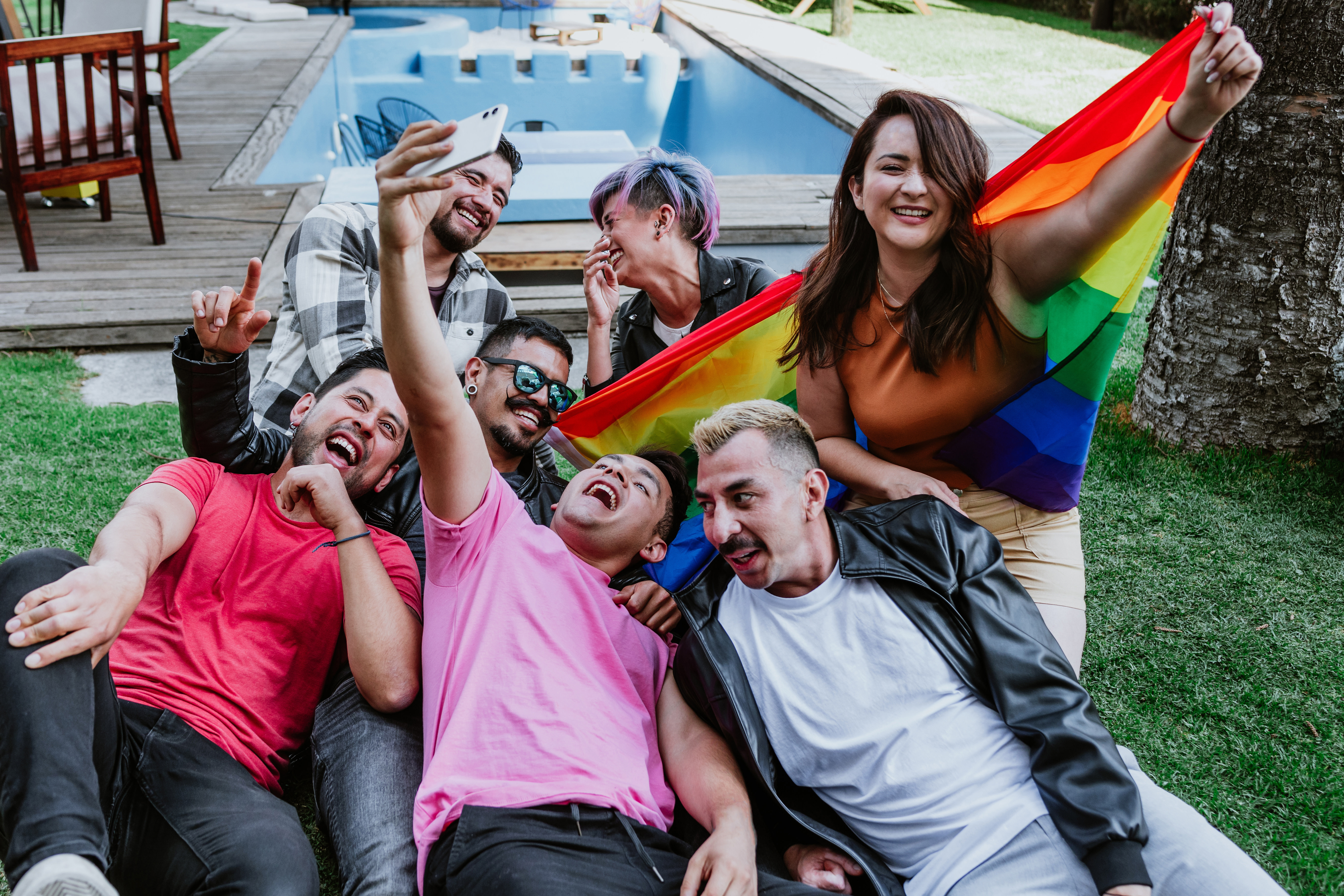 Group of LGBTQ people holding a rainbow flag and taking selfie