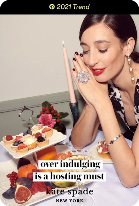 White woman with red lipstick looks at cake stand filled with treats