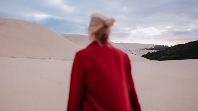 Woman in red coat walks in the desert