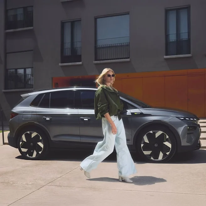 A female walking in front of a parked Skoda SUV.