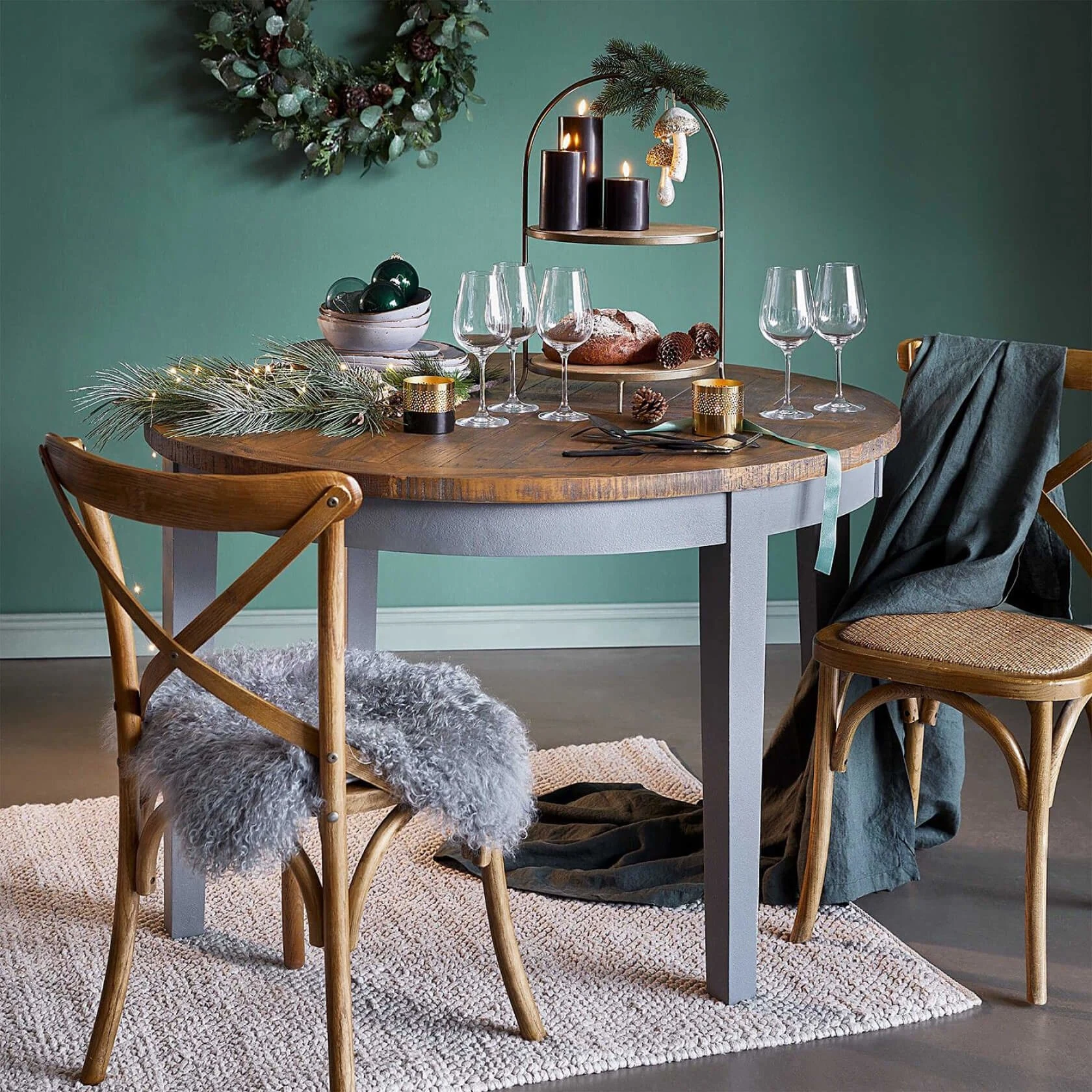 Zwei Holzstühle um einen kleinen runden Holztisch mit Dekor und Weingläsern