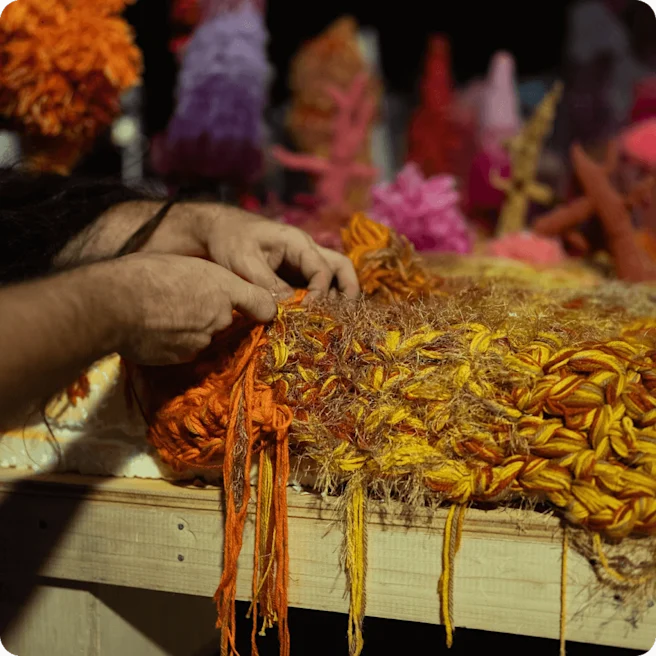 A closeup photo of a hand crocheting with orange yarn.