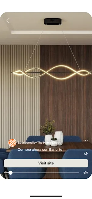 Modern dining room with a sleek, wave-shaped pendant light hanging from the ceiling. Blue upholstered chairs surround a wooden table, creating a warm, stylish ambiance.