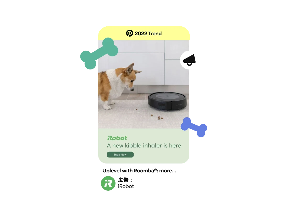 コーギー犬と床に散らばっているドッグフードを吸い取っている Roomba 掃除機が写っている広告ピン。広告には iRobot ロゴの下に「a new kibble inhaler is here」（フードを食べるマシン現わる）というコピーが入っている。ピンの上部に「2022 年のトレンド」バッジ付き。 