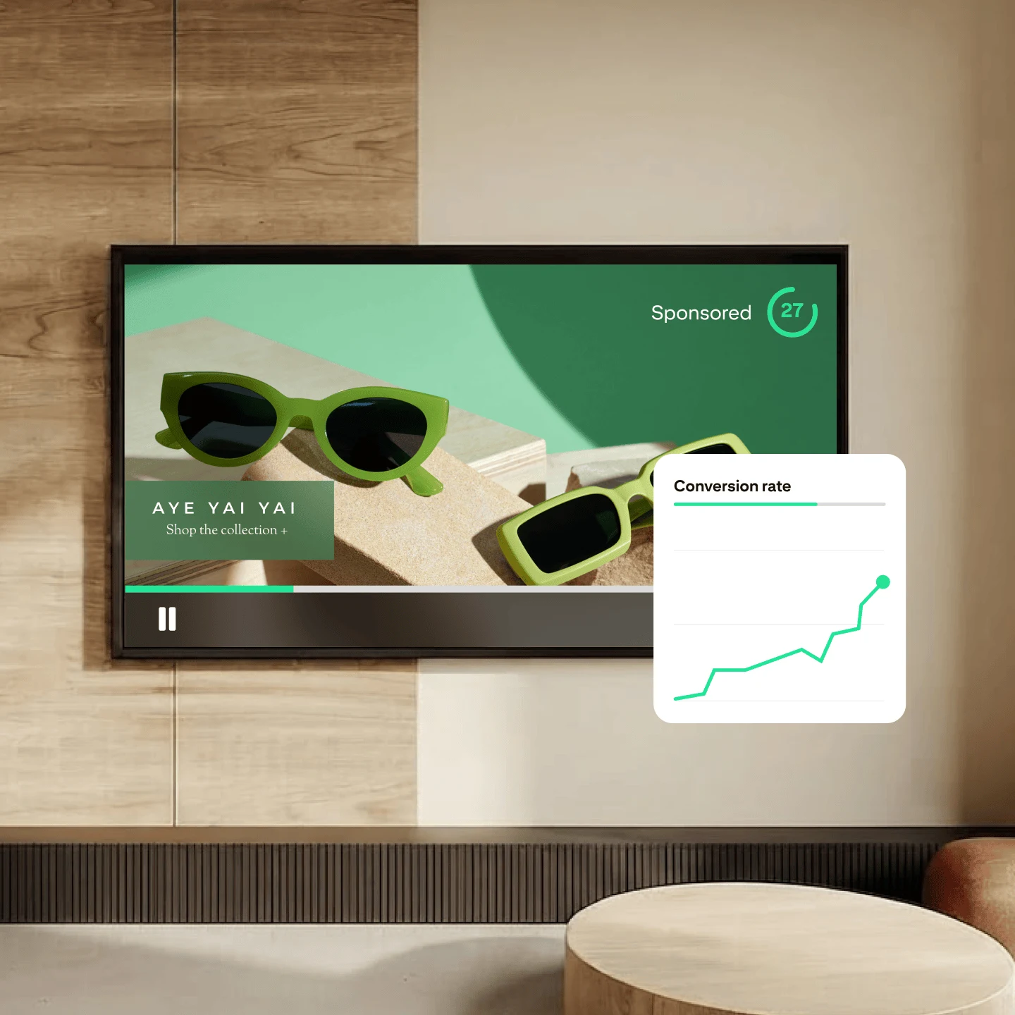 A tv mounted on the wall showing an advertisement for sunglasses; a graph that reads “conversion rate” is hovers to the right