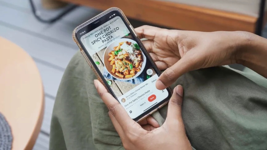 A pair of hands preparing to save a Pin featuring a recipe for spicy chorizo pasta.   