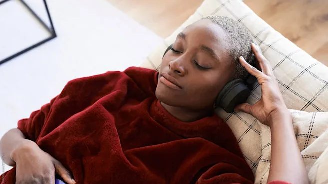 A Black woman is listening to music while reclining