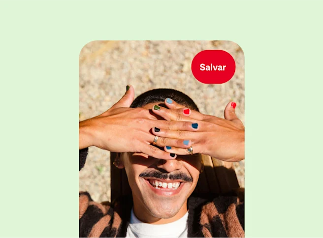 Uma pessoa branca sorrindo e protegendo os olhos contra o sol, com cada unha pintada de uma cor.