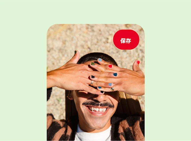 爪にばらばらな色のマニキュアを塗っている手を両目の上にかざして日差しを遮っている、笑顔の白人の人物。