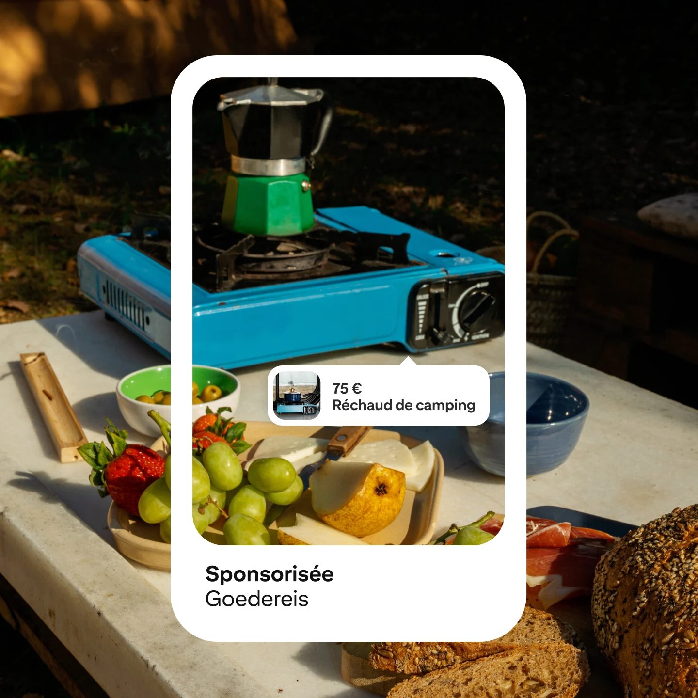 Image d’une maquette d’annonces Pinterest affichant un réchaud de camping portable bleu et argent au prix de 75 £, étiquetée «Réchaud de camping» et sponsorisée par «Goedereis». Différents fruits et aliments sont répartis autour du réchaud en plein air.