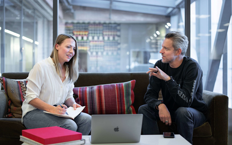 Two coworkers conversing on the couch