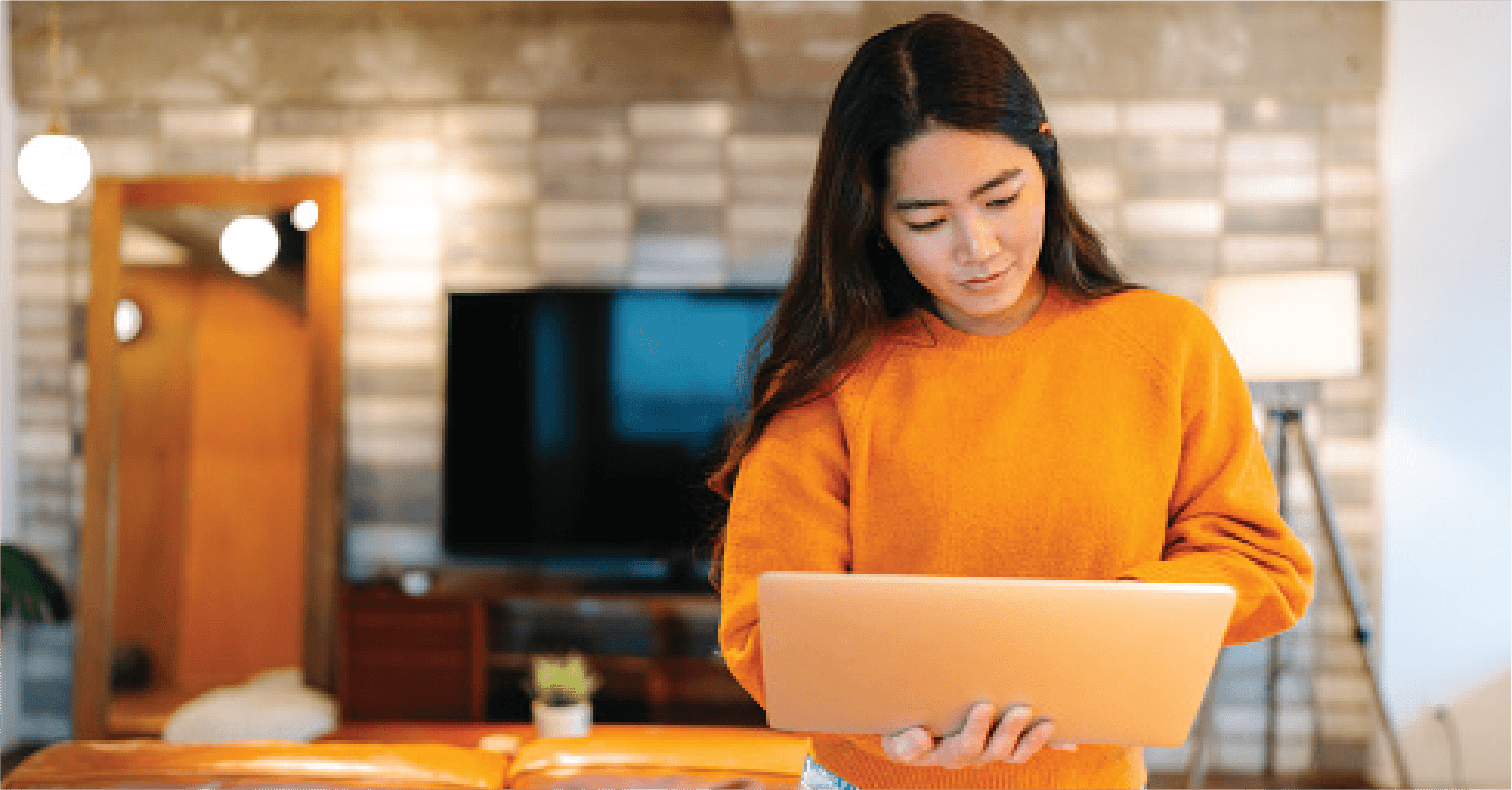 Lady in a orange jumper on her laptop.