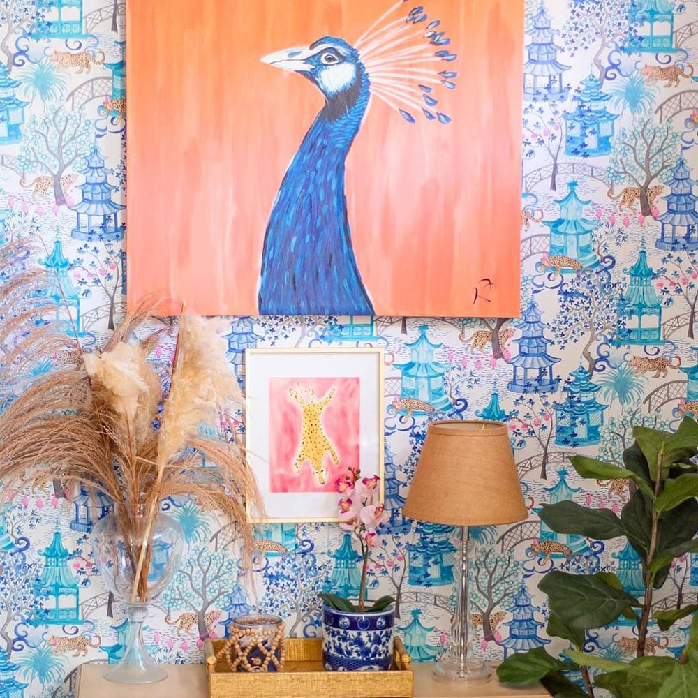 Wall with chinoiserie wallpaper and colorful wall art.