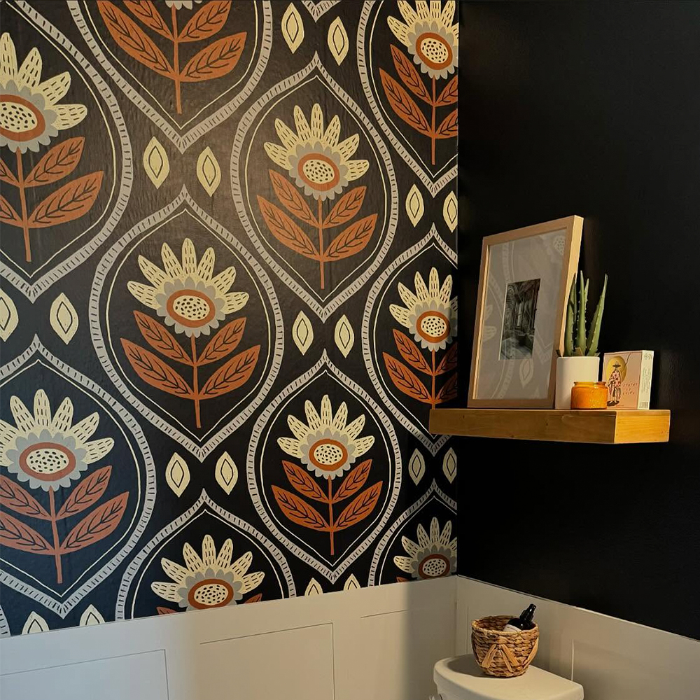 Bathroom with a black and burnt orange western wallpaper.
