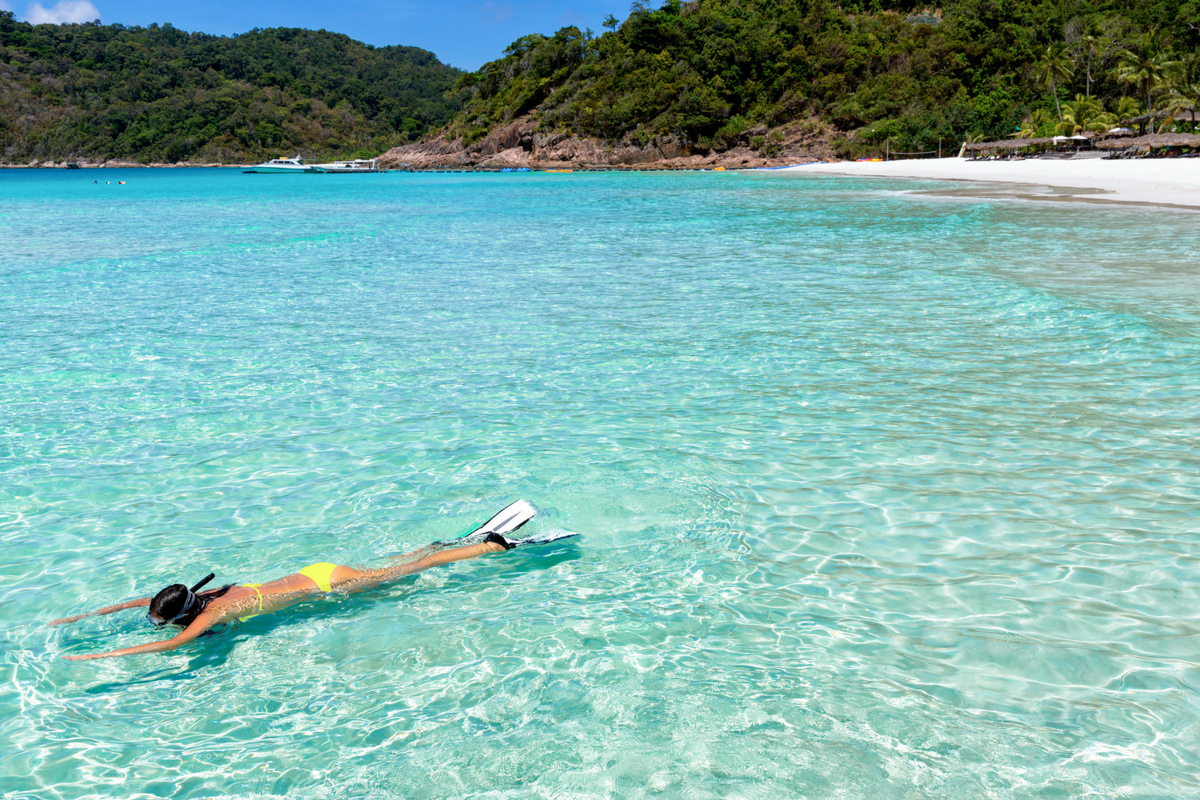 Woman snorkelling in the crystal-clear waters off the beach