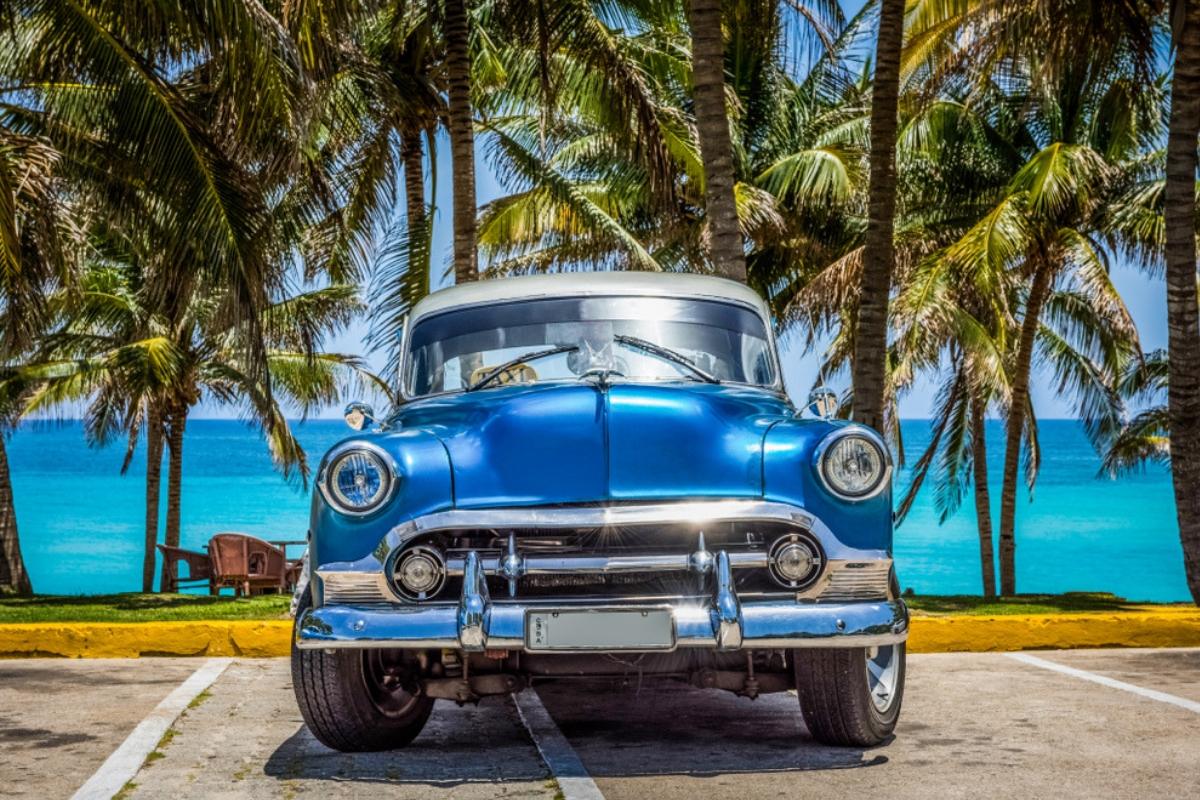 Classic blue American car parked by the beach overlooking the blue water