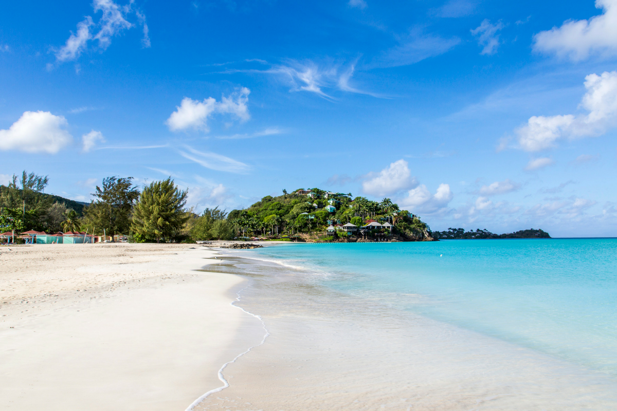 White sand beach with cottage-covered hillside in the background