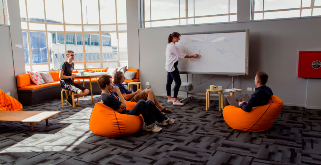 Students sitting on orange beanbags at The Orchard campus, learning Web Development.