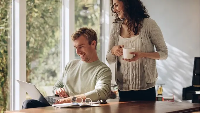 couple smiling while looking at a laptop together