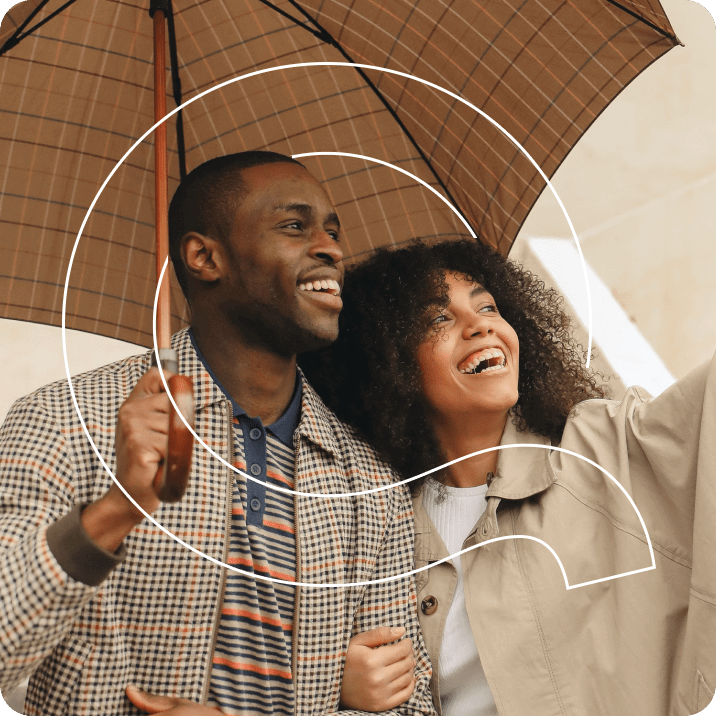 Q couple under an umbrella and laughing together.