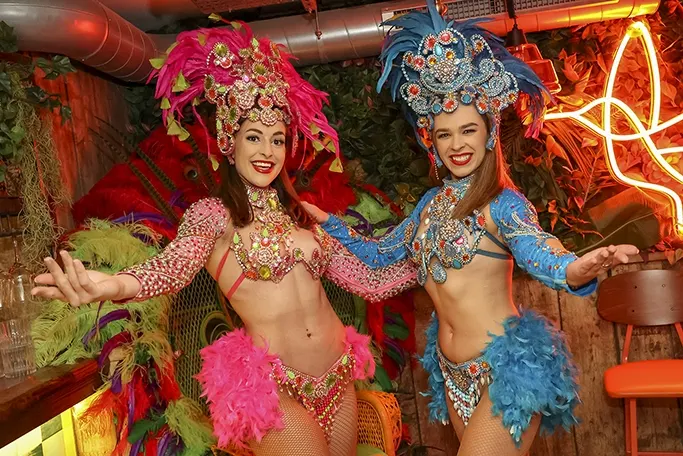 Two smiling women in full Brazilian Carnival regalia and feather headdresses Two smiling women in full Brazilian Carnival regalia and feather headdresses