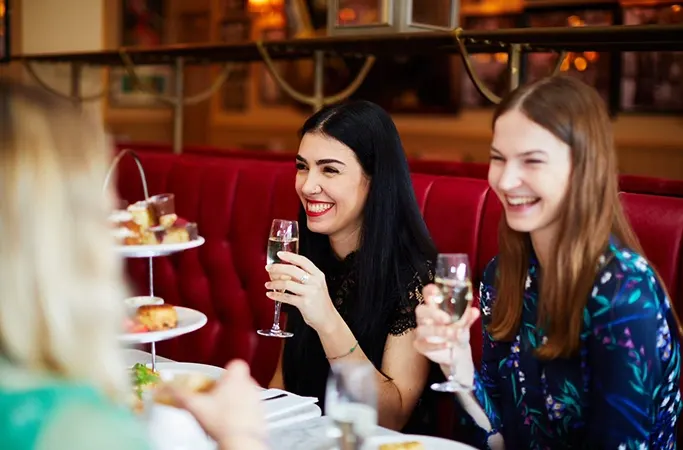 Smiling guests holding glasses of bubbly with their afternoon tea Smiling guests holding glasses of bubbly with their afternoon tea